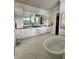 Bright bathroom with dual sink vanity, soaking tub, marble floors, and a glass enclosed shower at 1690 Palm Ave, Winter Park, FL 32789