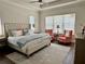 Inviting main bedroom with hardwood floors, tray ceiling and two pink upholstered chairs near the window at 1690 Palm Ave, Winter Park, FL 32789