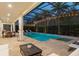Relaxing screened-in pool and spa with travertine tile, palm trees, and outdoor dining area at 8017 Chilton Dr, Orlando, FL 32836