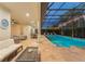 A covered pool with travertine tile and string lights offers a relaxing evening ambiance at 8017 Chilton Dr, Orlando, FL 32836