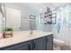 Bright bathroom with a blue vanity, white sink, decorative shelving, and a shower/tub combo at 12651 Winding Woods Ln, Orlando, FL 32832