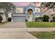 Charming two-story home with a gray exterior, arched entryway, and a well-manicured front yard at 12651 Winding Woods Ln, Orlando, FL 32832