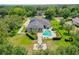 An aerial view shows a luxury home with a swimming pool, hot tub, fire pit, and lush landscaping at 13710 Lake Cawood Dr, Windermere, FL 34786