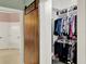 Walk-in closet with custom shelves, organized hanging racks, and a rustic sliding barn door entrance at 13710 Lake Cawood Dr, Windermere, FL 34786