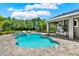 Backyard pool area featuring a covered outdoor kitchen and beautiful landscaping with sun loungers at 13710 Lake Cawood Dr, Windermere, FL 34786