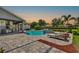A covered outdoor kitchen sits beside a pool and sun loungers in a luxurious backyard setting at 13710 Lake Cawood Dr, Windermere, FL 34786