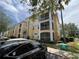 A condominium building with multiple screened lanais, lush greenery, and car parking at 1420 Lake Shadow Cir # 9207, Maitland, FL 32751