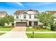 Charming two-story home with manicured lawn, lush landscaping, brick driveway, and a two car garage at 14883 Golden Sunburst Ave, Orlando, FL 32827