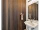 Stylish powder room showcases modern wood paneling, a pedestal sink, and a decorative mirror at 150 E Robinson St # 801, Orlando, FL 32801