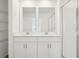 Bathroom with a double vanity, two mirrors, and a glass shower at 16434 Bird Of Paradise Ave, Clermont, FL 34714