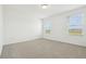 Bright bedroom features neutral carpet, white walls, and natural light from the two windows at 16434 Bird Of Paradise Ave, Clermont, FL 34714