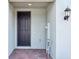 Close-up of a modern gray front door with a brick paver entry and decorative outdoor lantern at 16434 Bird Of Paradise Ave, Clermont, FL 34714