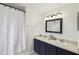 Bright bathroom featuring dual sinks with dark blue cabinets and a shower with a curtain at 360 Coventry Estate Blvd, Deltona, FL 32725