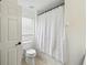 Clean bathroom featuring a toilet, window, and shower with a white curtain at 360 Coventry Estate Blvd, Deltona, FL 32725