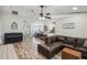Inviting living room featuring wood-look floors, ceiling fan, open layout, and a comfortable leather sofa at 360 Coventry Estate Blvd, Deltona, FL 32725