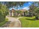 Exterior front elevation of the home with a circular driveway, lawn and tropical landscaping at 8740 Ingleton Ct, Orlando, FL 32836