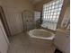 Bright bathroom featuring a glass block window, tub, and a separate shower at 1091 Hampstead Ln, Ormond Beach, FL 32174
