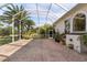 Covered brick patio next to the house with view of mature trees and tropical plants at 1091 Hampstead Ln, Ormond Beach, FL 32174