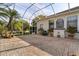 Covered brick patio next to the house with view of mature trees and tropical plants at 1091 Hampstead Ln, Ormond Beach, FL 32174