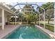 Beautiful covered pool with waterfall feature and relaxing view of mature trees and tropical plants at 1091 Hampstead Ln, Ormond Beach, FL 32174