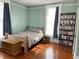 Comfortable bedroom featuring a wooden bed, hardwood floors, natural light, and a full bookcase at 209 E 4Th St, Sanford, FL 32771