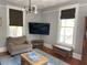Comfortable living room with hardwood floors, gray walls, large windows, and a flatscreen television at 209 E 4Th St, Sanford, FL 32771