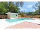 Backyard pool featuring turquoise water, a small pool house, privacy fence, and a brick patio area at 2637 Florence St, Orlando, FL 32818
