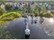 Picturesque aerial shot of a pier leading to a gazebo on a lake with lily pads and residential buildings at 3480 Soho St # 107, Orlando, FL 32835