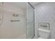 Bright bathroom features a tiled shower with sliding glass doors and patterned wallpaper at 4139 S Atlantic Ave # B707, New Smyrna Beach, FL 32169