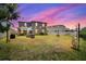 Expansive backyard featuring an outdoor patio, lush lawn, charming string lights, and privacy fence under a beautiful sky at 5637 Beggs Road, St Cloud, FL 34771