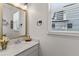 Bright half bathroom with white cabinets, granite countertop, a gold mirror, and a window at 5637 Beggs Road, St Cloud, FL 34771