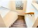 Carpeted staircase with white trim, wood handrail, and unique wall art creates a stylish and inviting transition between floors at 5637 Beggs Road, St Cloud, FL 34771
