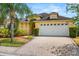 Charming yellow single-story home with a two-car garage, lush landscaping, and a brick paver driveway at 650 Old Bridge Cir, Davenport, FL 33897