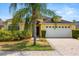 Charming yellow single-story home with a two-car garage, lush landscaping, and a brick paver driveway at 650 Old Bridge Cir, Davenport, FL 33897