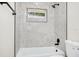 Modern bathroom tub and shower with marble tiles, black hardware and a window at 4710 Hatteras Ct, Orlando, FL 32808
