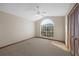 Bright bedroom with a large arched window, neutral carpet, ceiling fan, and closet with paneled doors at 11160 Sylvan Pond Cir, Orlando, FL 32825