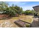 Spacious backyard showcasing a brick wall, mature trees, and an in-ground garden at 1134 Shaffer Trl, Oviedo, FL 32765