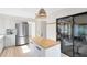 Open kitchen with stainless steel refrigerator, light wood floors and access to sunroom at 1134 Shaffer Trl, Oviedo, FL 32765