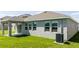 A backyard features a covered patio adjacent to a house with large windows and simple landscaping at 1163 James Paul Rd, Davenport, FL 33837