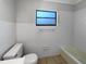 Clean, all-white bathroom featuring a tub, toilet and large window at 1249 12Th St, Clermont, FL 34711