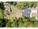 An overhead view of the single-Gathering home highlighting a well-maintained yard, detached garage, and surrounding trees at 131 Autumn Ct, St Cloud, FL 34771