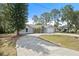 Landscaped single-story home with mature trees and a curved driveway leading to an attached two-car garage at 131 Autumn Ct, St Cloud, FL 34771