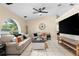 A bright, furnished living room with tile floors, ceiling fan, and an arched window overlooking the front yard at 131 Autumn Ct, St Cloud, FL 34771
