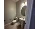 A simple, modern powder room with a pedestal sink and a round mirror at 1360 Twelve Oaks Rd, St Cloud, FL 34771