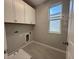 Functional laundry room with upper cabinets and a utility sink, offering convenience and storage space at 1360 Twelve Oaks Rd, St Cloud, FL 34771
