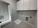 A tidy laundry room with overhead cabinets and connections for a washer and dryer unit at 1360 Twelve Oaks Rd, St Cloud, FL 34771