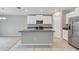 Open floor plan featuring granite island with stainless steel sink, white cabinetry, and view of carpeted living area at 14066 Sw 60Th Ter, Ocala, FL 34473