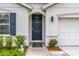 Close-up of front door and welcome mat, with blue shutters and manicured landscaping at 149 Hickory Course Cir, Ocala, FL 34472
