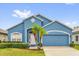 Charming single-story home boasts a light blue exterior and a well-manicured lawn with tropical landscaping at 1730 Ribbon Falls Pkwy, Orlando, FL 32824