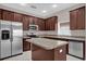 The renovated kitchen includes stainless steel appliances, an island, tile floors, and ample storage within dark wood cabinetry at 1730 Ribbon Falls Pkwy, Orlando, FL 32824